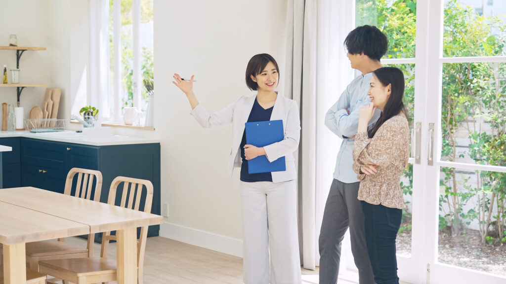 ショールームで受付スタッフがお客様ご夫婦を笑顔でご案内する場面(デモ)